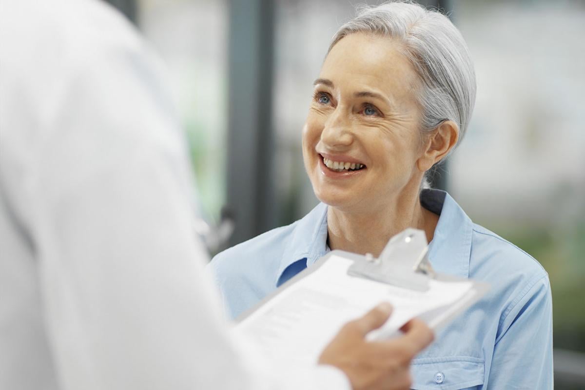 Doctor talking to mature patient while holding clipboard
