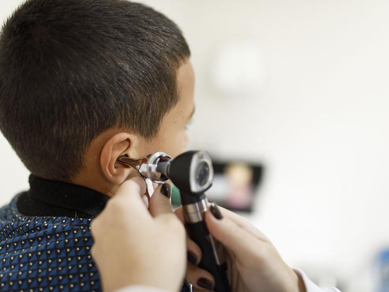 Doctor checking little boy's ears with an otoscope