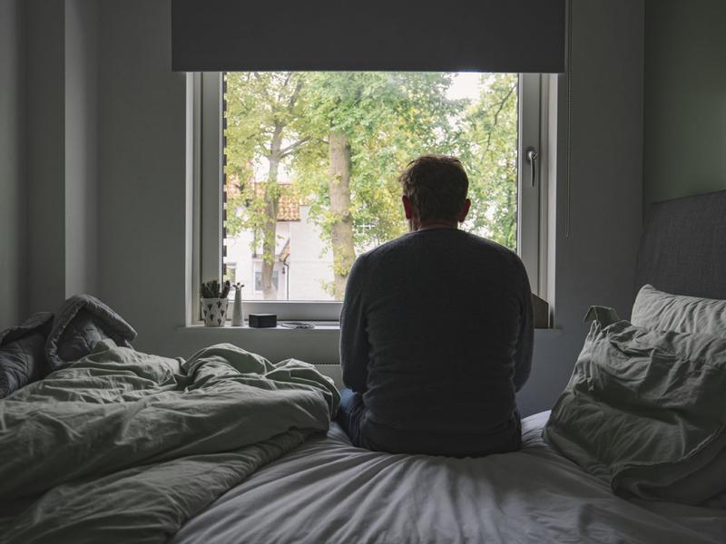 Man sitting on his bed looking out of the window