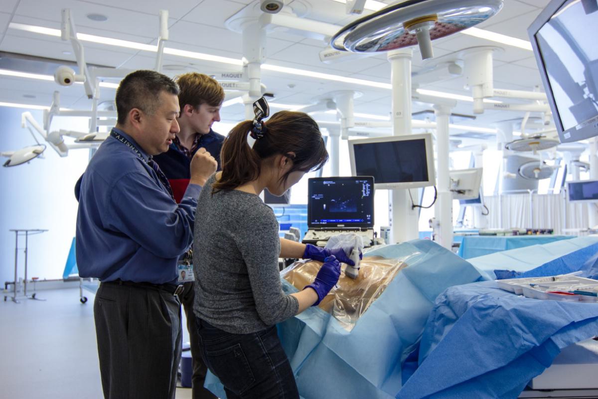 David H. Chong, MD, working with students Christopher Hoeger and Arin Kim during a skills class.