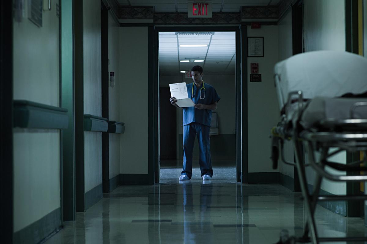 Physician standing in the doorway of a hospital hallway. 